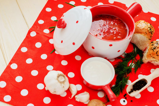 Ukrainian national cuisine , red borscht with sour cream , herbs , garlic and pumpushki on a wooden background