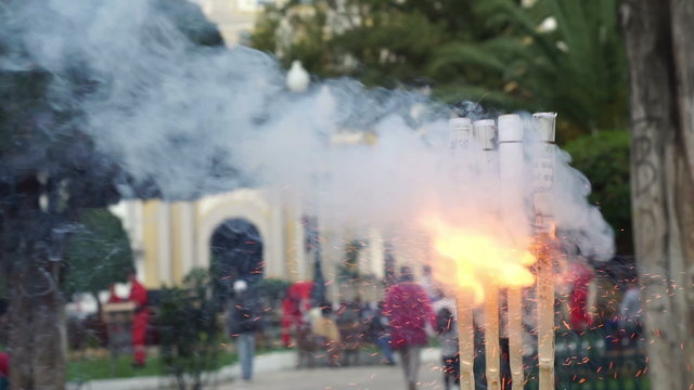 Closeup shot of an anonymous man lighting some artisanal firecrackers with a church in the background as the fireworks are used in ceremonies and during worship to ward off evil spirits.