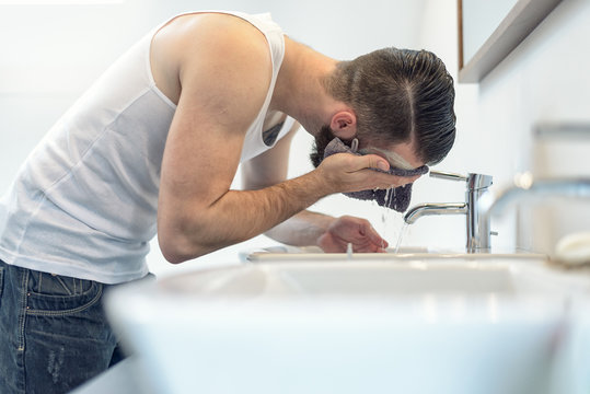 Mann mit Bart wäscht sein Gesicht