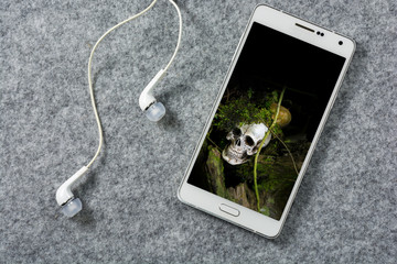 Aerial view of white smart phone and white headphones with human
