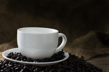 Coffee beans and white coffee cup in wooden background. Still Li