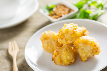Crispy fried corn ball in a white plate on wooden table,Vegetari