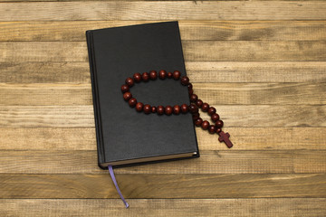 bible book and rosary  on dark wood planks