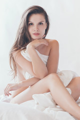Obraz premium Beautiful sexy blonde woman in white lingerie lying on bed