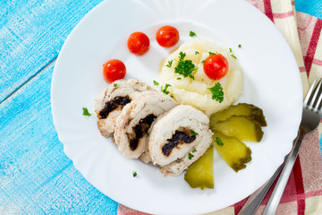 Chicken roll with prunes and nuts on a wooden table