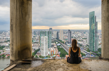 young women meditates in yoga position on high building. Unique concept of meditation, spirituality and balance