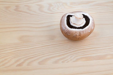 A chestnut mushroom on a wooden cutting board