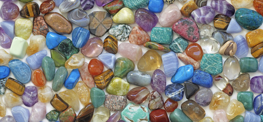 Multicolored tumbled crystal stones background - a large quantity of different colored healing tumbled gem stones making up a backdrop for use as a background © Nikki Zalewski