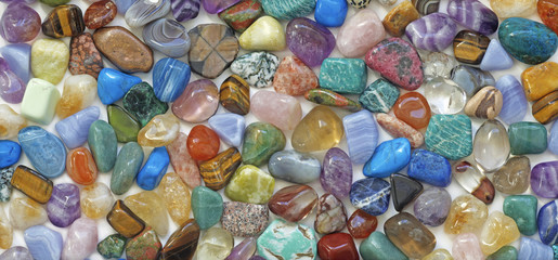 Multicolored tumbled crystal stones background - a large quantity of different colored healing...