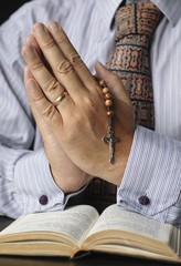 Praying unidentified Catholic  man holds a rosary in his hands