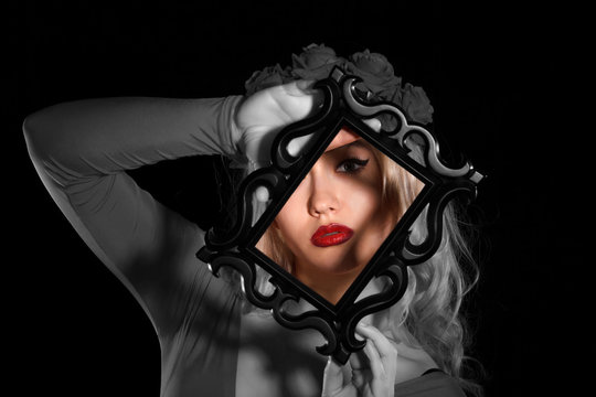 Pretty young woman holding a frame in front of her face