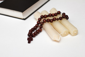 bible book and rosary with three candle