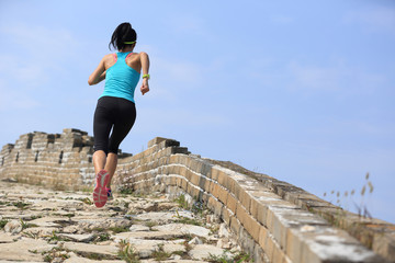 woman runner athlete running on trail at chinese great wall . woman fitness jogging workout wellness concept.