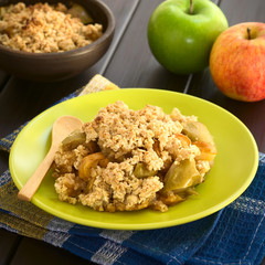 Freshly baked apple crumble or crisp, photographed on dark wood with natural light (Selective...