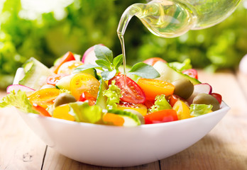 olive oil pouring over vegetable salad