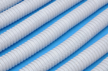 White plastic corrugated pipes on blue background