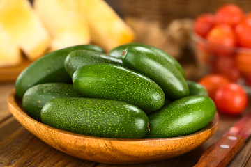 Finger or cocktail avocados on wooden plate with baguette slices and cherry tomatoes in the back  (Selective Focus, Focus on the avocado on the top)