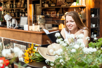 smiling girl sitting at summer terrace and reading book
