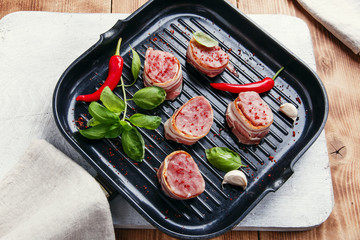 raw meat tenderloin medallions with bacon on the grill