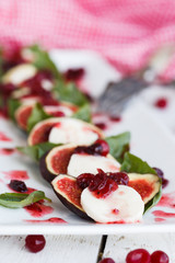 Salad Caprese with mozzarella, cranberries, Basil and balsamic vinegar arranged on a white plate