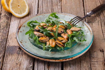 Salad with mussels and arugula on a glass plate with olive oil and lemon.selective focus