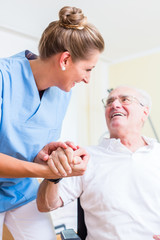 Nurse holding hand of senior man in rest home