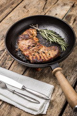 Roasted beefsteak with bunch of rosemary on grill pan