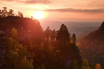 Fototapeta na wymiar Autumn sunset in rocks. View over sandstone rocks to fall colorful valley of Bohemian Switzerland.