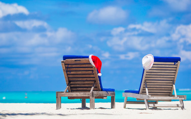 Beach loungers with red Santa and straw hat background beautiful turquoise sea