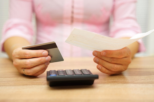 woman is holding bill and credit card in hands  and calculating