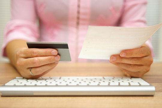 woman is using debit or credit card to pay online the bills and