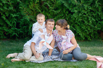 Young family sitting on the grass in a park with toys