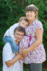 Fototapeta na wymiar Happy family. Pregnant mother with her husband and son in the park