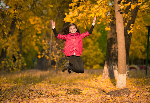 Smiling girl with autumn maple leaves at fall outdoors