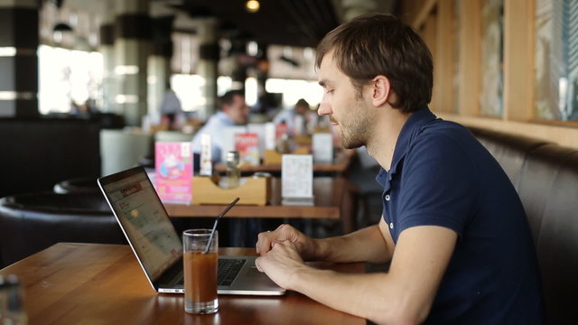 serious man with laptop in cafe