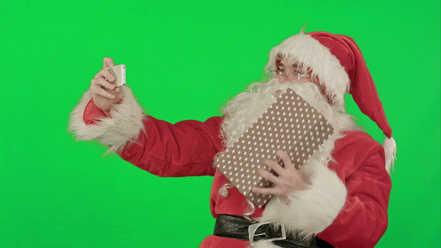 Santa Claus make selfie, holding a big present on a Green Screen Chrome Key