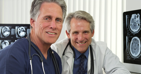 Senior doctors sitting at desk smiling