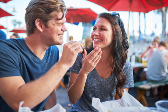 Playful Couple On Date Eating French Fries