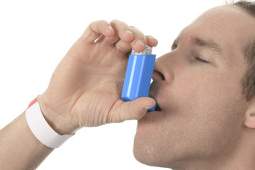 Young man using an asthma inhaler as prevention