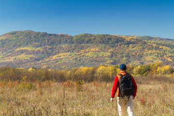 Male tourist with backpack sotret on the horizon in autumn