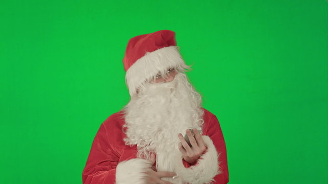 Santa claus reads and sends text messages from his cell phone  on a Green Screen Chrome Key