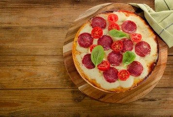 Salami Pizza served on rustic wooden table.