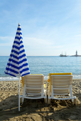 Two chairs and closed umbrella on  the beach