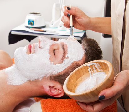 Therapist Applying A Face Mask To A Beautiful Young Man In A Spa