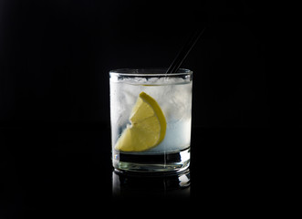 Cocktail with lemon and ice on the black background