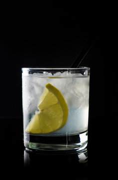 Cocktail with lemon and ice on the black background
