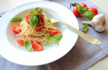 Italian spaghetti pasta with tomato sauce and meat on a white plate
