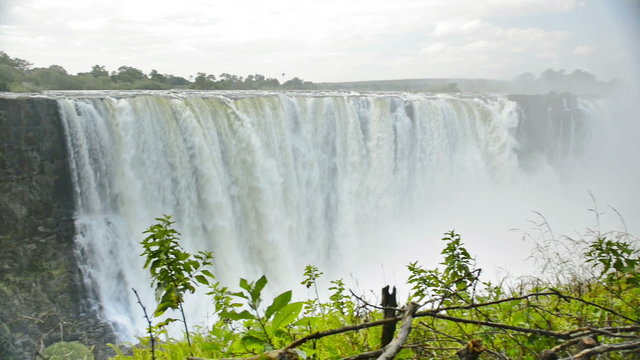 Victoria Falls or Mosi-oa-Tunya flowing waterfall in southern Africa on the Zambezi River at the border of Zambia and Zimbabwe in high definition panning footage with ambient audio. 