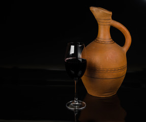 Ceramic jug for wine and a glass of red wine