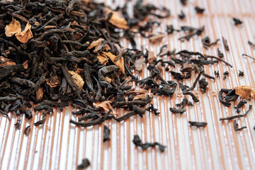 Dry tea leaves spread on light brown color background